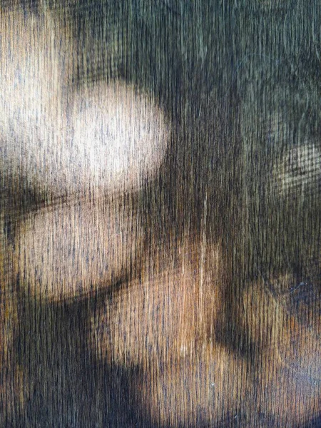 Parlak, benekli güneş ışığı demetleri koyu ahşap bir yüzeye düşerek yüksek kontrastlı soyut desenler oluşturur. Işık, doğal ahşabın derinliğini, dikey yapısını ve dokusunu vurgular.