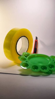 Kırmızı bıçak ve yeşil plastik nesnelere sarılı sarı şeritten bakarak yaratıcı yakın çekim