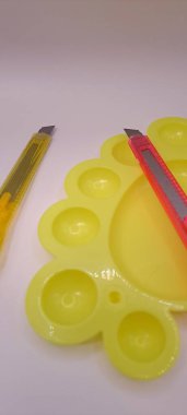 Sanat ve zanaat projeleri için sarı bir plastik karıştırma paletinde uzanan parlak kırtasiye kesicilerini yakın çekim