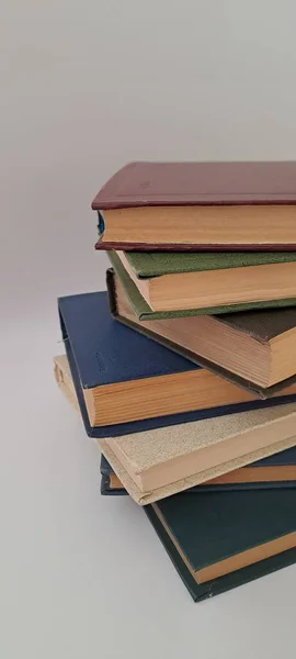 Tarafsız bir arkaplanda eski sarı kağıt sayfaların dokusunu gösteren bir yığın antika ciltli kitap.