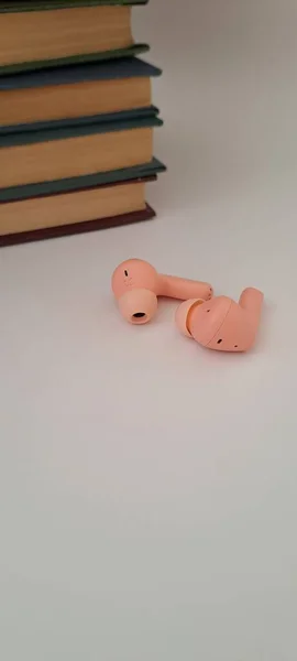 Pembe Kablosuz Kulaklıklar ve Çalışma ve Rahatlama İçin Kitap Yığını