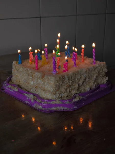 a vertical shot of a burning candle with a candle on the cake