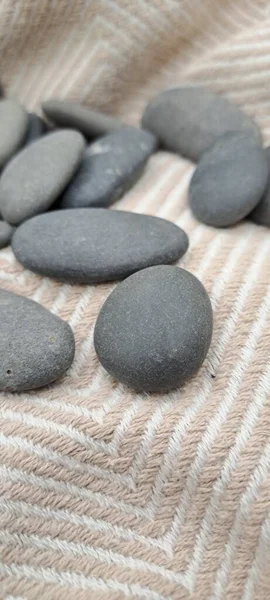 Smooth Grey River Stones on Beige Patterned Fabric Background