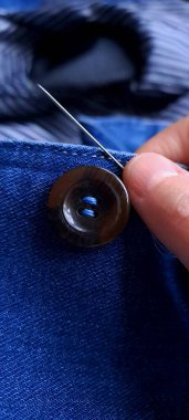 Kot pantolon düğmesi dikebilen bir iğneyle terzilik ve giysi onarım konsepti