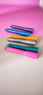 Pembe ve gri arka planda renkli keçeli kalemler. Yaratıcı projeler için çift tonlu bir yüzeye yatay olarak dizilmiş metalik ve parlak renkli çizim kalemleri koleksiyonu