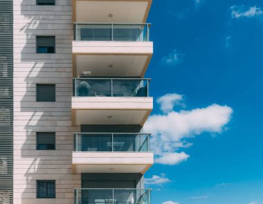 Balkonlar ve bulutlu mavi gökyüzü. İsrail 'de bir yerleşim yerinin parçası. Güneşli bir günde modern apartman binaları. Mimari detaylar. Balkonlu modern beyaz bina. 
