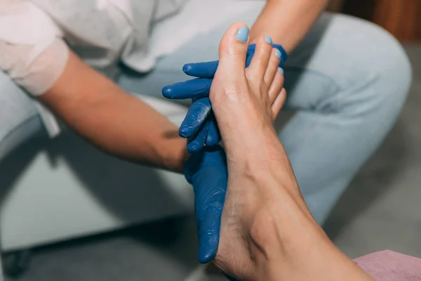 Close-up of Pedicure in salon. Foot care treatment and nail. Foot massage during the pedicure process. Master in blue gloves makes pedicure with manicure machine. Concept of beauty care and health