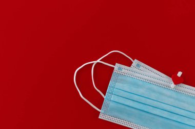 İki tıbbi maske, kırmızı arka planda kalbi olan bir mandalla bağlanmış ve yazı için boşluk bırakılmış. Aşk bayrağı teması. Sevgi dolu, olumlu duygular. Kutlama ve aşk kavramı.