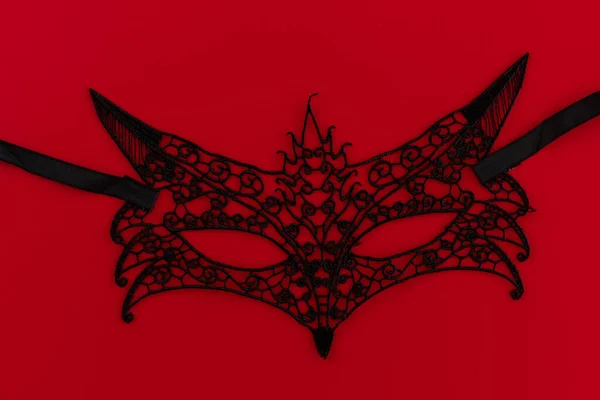 Black sexy fox mask on a red background with space for text. Concept of Valentine\'s Day. Copy space, top view. The concept of Valentine\'s Day. Theme of love banner. Loving, positive emotions