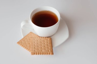 Bir fincan çay, çay tabağı ve beyaz arka planda iki kurabiye. Krakerli kahve fincanının üst görüntüsü. Kafe menüsü ya da restoran için güzel afiş. Sabah kahvaltısı. Güne kahveyle başla.