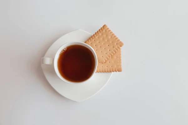 One white cup of tea with saucer and two cookies on white background. Top view of coffee mug with crackers. Nice banner for cafe menu or restaurant. Morning breakfast. Start the day with coffee