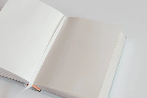 Open blank book on a white background with a bookmark. Notebook inside mockup. Empty open book in square format. Design concept - top view of white notebook with blank open