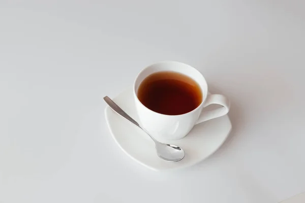 One white cup of tea with saucer and spoon on white background. Top view of coffee mug. Nice banner for cafe menu or restaurant. Morning breakfast. Start the day with coffee