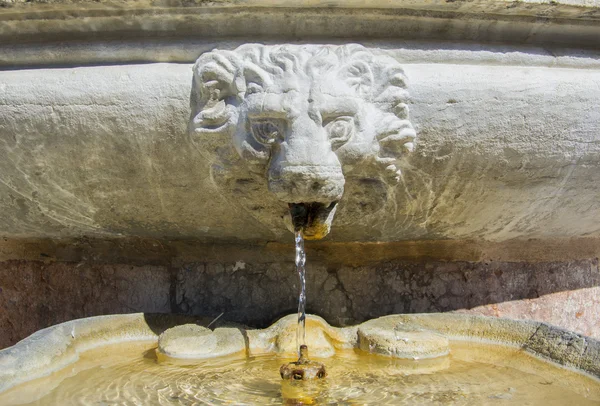 Ancient stone lion head water fountain on an old street in Rome