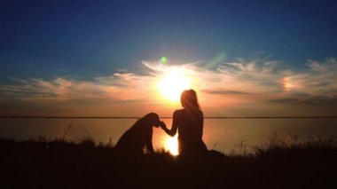 Kadın köpeğini gün batımında sahilde hugs