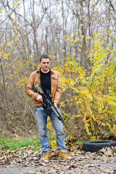 Hombre pensativo con un arma automática en el bosque — Foto de Stock