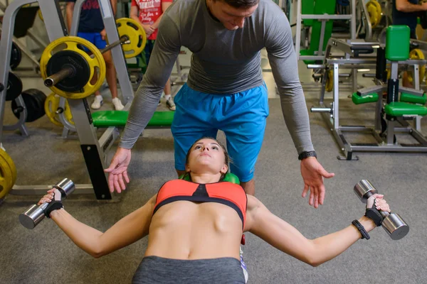 fitness girl at the gym with free weights and trainer