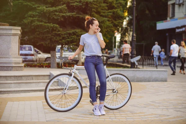 Девушка с велосипедом разговаривает по телефону — стоковое фото