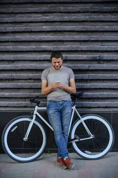Парень с велосипедом и починить телефон — стоковое фото