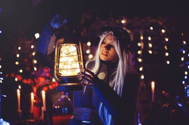 Karanlık ormanda sihirli büyüleri olan Cadılar Bayramı elfi. Şapkalı ve elf kostümlü güzel genç bir kadın sihirli bir kimya tutuyor. Cadılar Bayramı Sanat Tasarımı