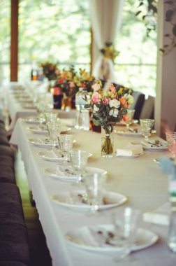 Beyaz bir masanın üzerinde pembe ve beyaz vazoların içinde çiçek aranjmanı, kopyalama alanı. Düğün süslemeleri, tatil konsepti