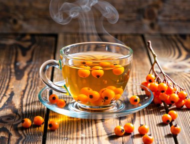 Kırsal bir ahşap masaya konmuş, buharı tüten bir bardak karabatak çayı. Taze portakal meyveleri ve yeşil yapraklarla çevrili bu canlı bitkisel karışım doğal ısı ve vitamin enerjisi yayar..