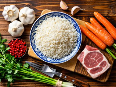 Tahta bir masada çiğ et, havuç, sarımsak, maydanoz ve kırmızı böğürtlenlerle çevrili beyaz pirinç kasesinin üst görüntüsü. Sağlıklı bir yemek için mükemmel malzemeler..