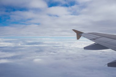 Kalın bir bulut örtüsünün üzerinde bir uçak kanadı görünüyor.