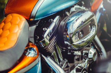 Canlı bir turuncu ve deniz mavisi benzin deposu, kahverengi bal peteği desenli deri koltuk ve büyük bir krom hava temizleyicisi içeren özel yapım bir motosikletin yatay yakın plan çekimi..