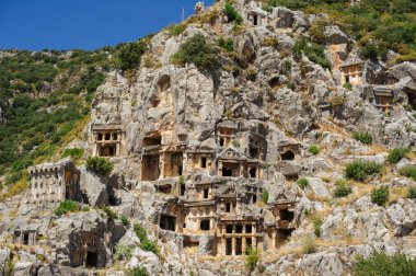 Türkiye 'nin Myra kentindeki dikey kaya yüzeyine sayısız mezar kazınmış antik Lycian mezarlığının yatay geniş açılı bir görüntüsü..