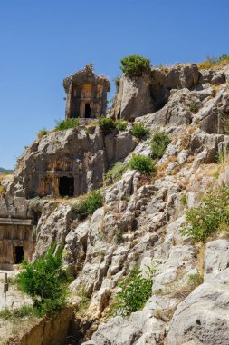 Antik taş mezarların ve lahitlerin dikey bir görüntüsü Myra 'nın doğal kayalık yüzeyine parlak güneşli bir gökyüzü altında entegre edildi..