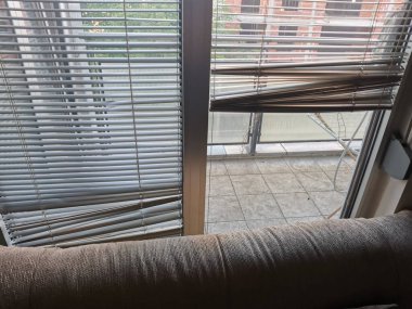 Yassı pencere, kanepenin ötesindeki balkon kiremitleriyle kör olur.