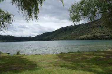 Huzurlu su ormanlık yamaçların altında orman yamaçları yamaçtaki çim çayırlarının altında dinleniyor.