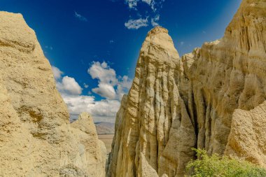Sunlit canyon walls rise beneath scattered clouds desert arid geology erosion