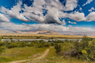 Remote countryside shows winding path distant hills landscape meadow grassland