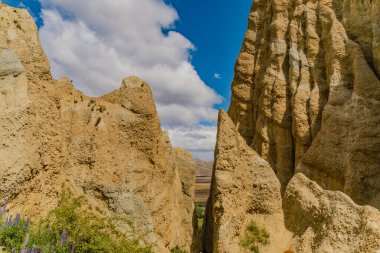 Güneşli vadi parlak gökyüzünün altındaki engebeli duvarları ortaya çıkarıyor. Kurak çöl jeoloji katmanı.