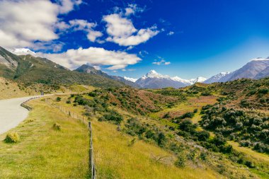 Güneşli kırsal bölgeler, tepe noktalarının yakınındaki kıvrımlı doğa yolculuğunu gösteriyor.