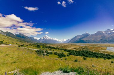 Uzak kırsal bölgeler, açık arazilerin ötesinde engebeli tepeler gösteriyor.