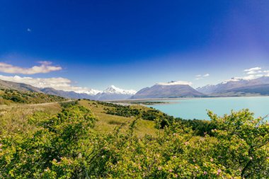 Uzak kırsal bölgelerde engebeli dağların, dağların, vadilerin ve çayırların yanında parlak sular görülüyor.