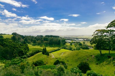 Güneşli kırsal vadi uzak ufuktaki çayırlara doğru uzanıyor.
