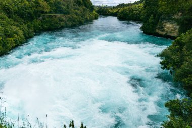 Dar yeşil kanyon akıntısı çağlayan köpükler arasından güçlü su taşar.