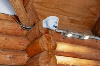 İçerideki aygıt, tavan altındaki rustik kirişleri izler. Güvenlik lenslerinin konutlarını aydınlatır.