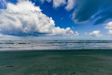Karamsar kıyı dalgaları yüksek gökyüzü fırtınalı deniz suyu dalgaları altında gösteriyor.
