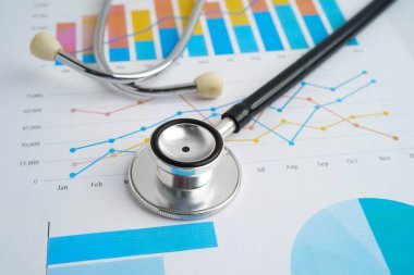 Çizelge ya da grafik kağıdı, Finansal, hesap, istatistik ve iş verileri medikal sağlık kavramı üzerine steteskop ve ABD doları banknotları.