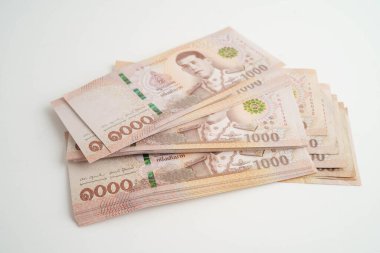 Asyalı kadın Tayland baht banknotlarını sayıyor ve elinde beyaz arka planda tek başına duruyor..