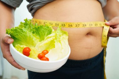 Koca göbekli, şişman, kilolu ve sağlıklı yiyecekleri olan Asyalı bir kadın..