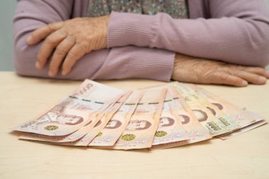 Emekli Asyalı yaşlı kadın para sayıyor ve aylık giderleri ve tedavi ücretini düşünüyor.