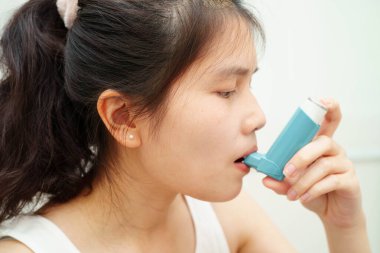 Astım ve kronik obstrüktif akciğer hastalığı KOAH, Asyalı genç ölçülü doz solunum cihazı kullanıyor..