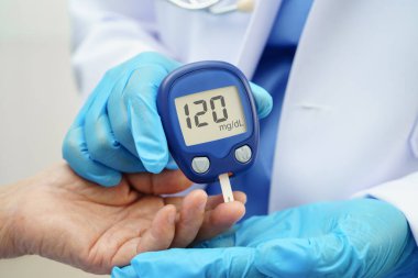 Diyabet tedavisinde kan şekeri seviyesini kontrol etmek için dijital glikoz ölçer kullanan Asyalı doktor.