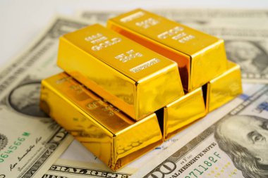 Gold bars on US dollar banknote money, finance trading investment business currency concept.